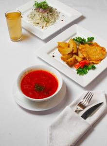 einen Tisch mit zwei Teller Essen und eine Schüssel Suppe in der Unterkunft Готель Україна in Lokhvytsya