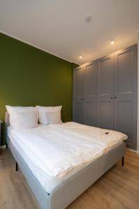 a bedroom with a white bed with a green wall at Im Herzen der Stadt - EG Wohnung in Paderborn
