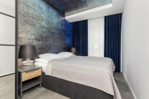 um quarto com uma cama e uma parede azul em Milionowa Loft Apartment with Parking in Łódź by Renters em Lódź