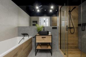 uma casa de banho com uma banheira, um lavatório e um chuveiro em Milionowa Loft Apartment with Parking in Łódź by Renters em Lódź