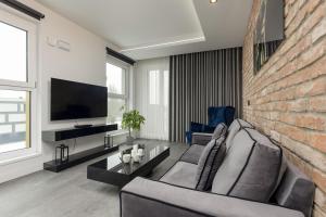 uma sala de estar com uma parede de tijolos e uma televisão em Milionowa Loft Apartment with Parking in Łódź by Renters em Lódź