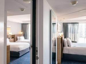 a hotel room with two beds and a mirror at Sofitel Gold Coast Broadbeach in Gold Coast