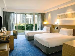 a hotel room with two beds and a balcony at Sofitel Gold Coast Broadbeach in Gold Coast