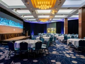 a conference room with tables and chairs and a screen at Sofitel Gold Coast Broadbeach in Gold Coast