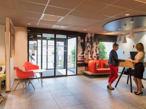 Ein Mann und eine Frau stehen in einer Lobby in der Unterkunft ibis Tours Nord in Tours