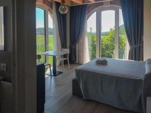 a bedroom with a bed and a table and windows at Tenuta da Rino - Agriturismo Barco Menti in Vicenza