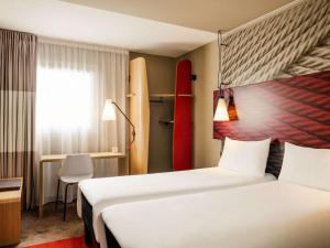 a hotel room with two beds and a surfboard on the wall at ibis Bordeaux Centre Bastide in Bordeaux