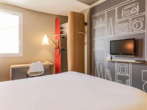 a bedroom with a bed and a tv on a wall at ibis Bordeaux Centre Bastide in Bordeaux