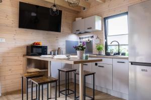 a kitchen with white cabinets and a counter with stools at Solo na wyspie, domki blisko morza Sobieszewo in Gdańsk