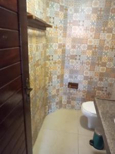 a bathroom with a toilet and a tiled wall at Mansao Santa Rita in Cumbuco