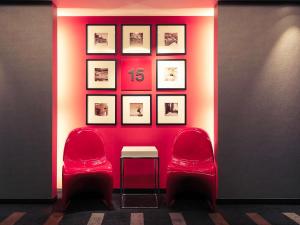 um quarto com duas cadeiras e uma mesa e uma parede com quadros em Mercure Hotel Sapporo em Sapporo