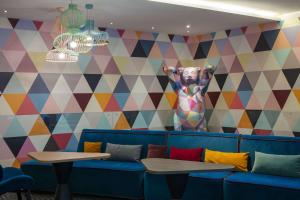 niebieska kanapa z dwoma stołami i kolorową ścianą w obiekcie Hampton by Hilton Berlin City West w Berlinie
