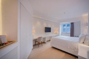 a white bedroom with a bed and a desk at Pagoda Lifestyle Hotel in Ischia