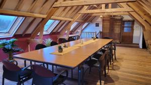 Una mesa grande y sillas en una habitación con techos de madera. en Altegaar, en Zottegem