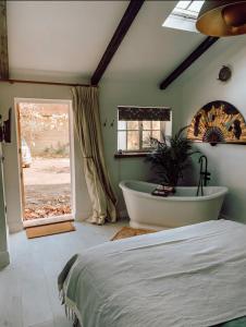 um quarto com uma cama, uma banheira e uma janela em Priory Cottage Stables em Cowden