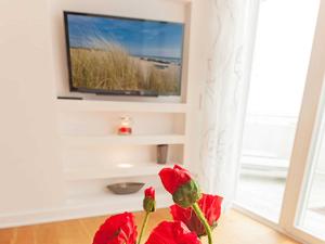 ザスニッツにあるOstseeresidenz Sassnitz F548 WG 5 mit Sauna, Terrasse, Meerblickのテレビ付きの部屋の赤い花
