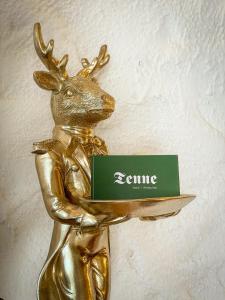 una estatua de bronce de un ciervo sosteniendo un cartel en Hotel Tenne, en Sankt Anton am Arlberg