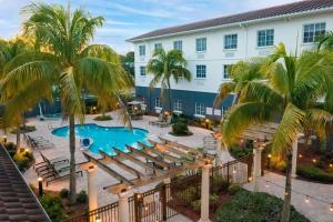 Blick auf ein Hotel mit Pool und Palmen in der Unterkunft Hilton Garden Inn at PGA Village/Port St. Lucie in Port Saint Lucie