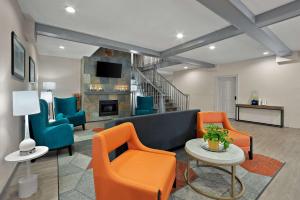 sala de estar con sofá azul y sillas de color naranja en Comfort Inn & Suites Santee I-95, en Santee