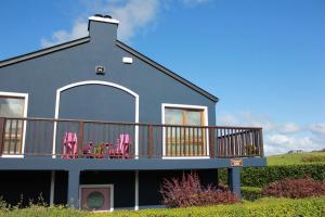 uma casa com uma varanda com cadeiras cor-de-rosa em Riverbank Rooms em Doolin