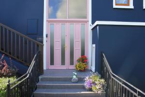 a pink door on a blue house with flowers at Riverbank Rooms in Doolin