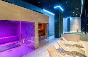 baño con iluminación púrpura y sillas frente a una ducha en Gran Hotel Bali en Benidorm