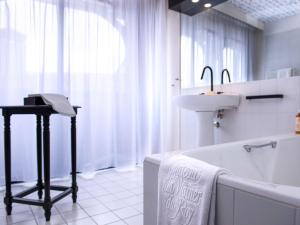 a white bathroom with a sink and a tub and a sink at Mercure Figeac Viguier du Roy in Figeac
