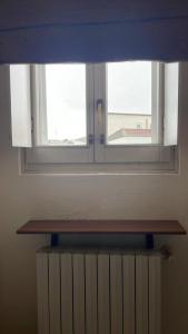ein Fenster in einem Zimmer mit einem Holzregal darunter in der Unterkunft A pochi passi dal centro in Novara