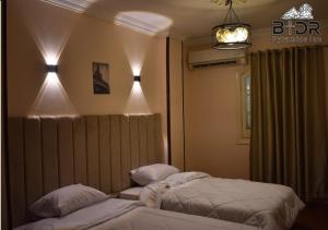 2 Betten in einem Schlafzimmer mit Lampen an der Wand in der Unterkunft King Badr pyramids in Kairo