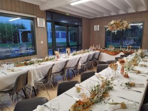 a row of tables in a banquet hall with white table linens at La Maison de Julise in Cossé-le-Vivien