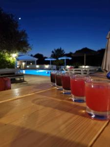 une rangée de verres sur une table en bois près d'une piscine dans l'établissement Blue Waves Corfu, à Kavos