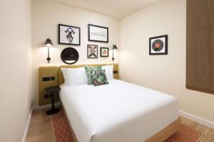 Una cama blanca en una habitación con cuadros en la pared. en Hampton By Hilton London Old Street, en Londres