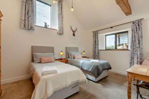 two beds in a room with two windows at Fox in Charlbury