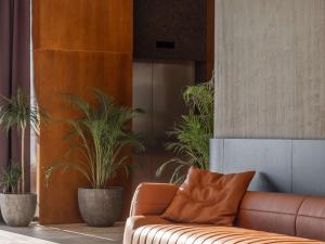 a brown couch in a room with potted plants at Mercure Prishtina City in Prishtinë