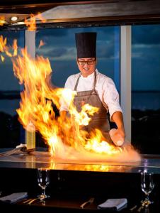 Szef kuchni przygotowuje jedzenie przed płomieniami. w obiekcie Hilton Cancun Mar Caribe All-Inclusive Resort w mieście Cancún