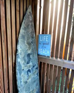 a surfboard leaned up against a fence with a sign at La petite cabane de Georges à Saint Brévin l'Océan in Saint-Brevin-les-Pins