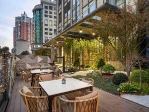 a patio with tables and chairs and buildings at Novotel Shanghai JingAn in Shanghai