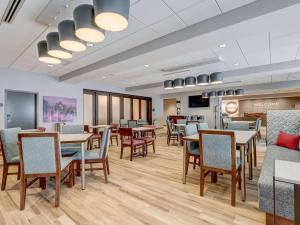 Hampton Inn & Suites Cincinnati Midtown Rookwood في سينسيناتي: غرفة طعام مع طاولات وكراسي وتلفزيون