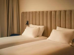 two beds with white pillows sitting next to each other at TRIBE Milano Malpensa in Vizzola Ticino