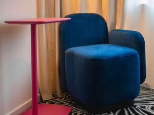 uma cadeira azul sentada ao lado de uma mesa vermelha em TRIBE Milano Malpensa em Vizzola Ticino