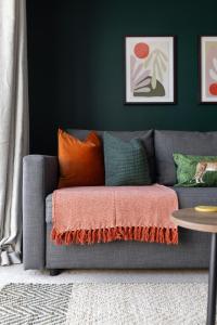 a gray couch with orange pillows in a living room at Modern 2-Bed Townhouse in Kirkdale in Liverpool