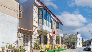 a building with blue windows and yellow chairs on a street at Lamur Hotel in Alaçatı