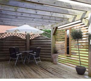 un patio avec une table, des chaises et un parasol dans l'établissement Surrounded by fields just 3 miles from Stratford - upon Avon - Alveston Pastures Retreat, à Stratford-upon-Avon