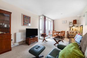 a living room with a couch and a tv at Penthouse 1BR flat wbalcony & city view, Walworth in London