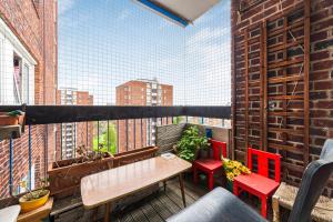 a balcony with a table and chairs and a large window at Penthouse 1BR flat wbalcony & city view, Walworth in London