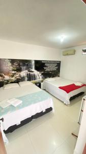 um quarto com duas camas e um quadro na parede em Pousada Caminho das Cachoeiras Pirenopolis em Pirenópolis