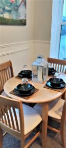 盧港的住宿－The Captain's Lodge Looe，一张木桌,上面有盘子和玻璃杯