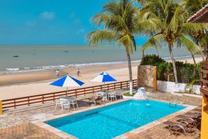 a swimming pool next to a beach with palm trees at Pousada Estrela da Luz Beach in Ceará-Mirim