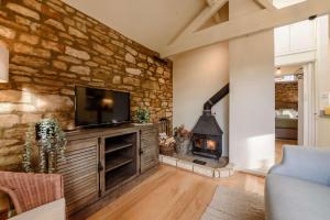 a living room with a stone wall with a fireplace at Oxbow Cottage in Stow on the Wold