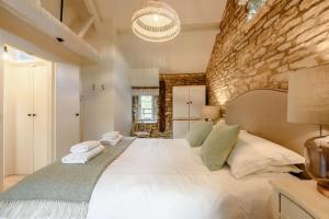 a bedroom with a large white bed with a stone wall at Oxbow Cottage in Stow on the Wold